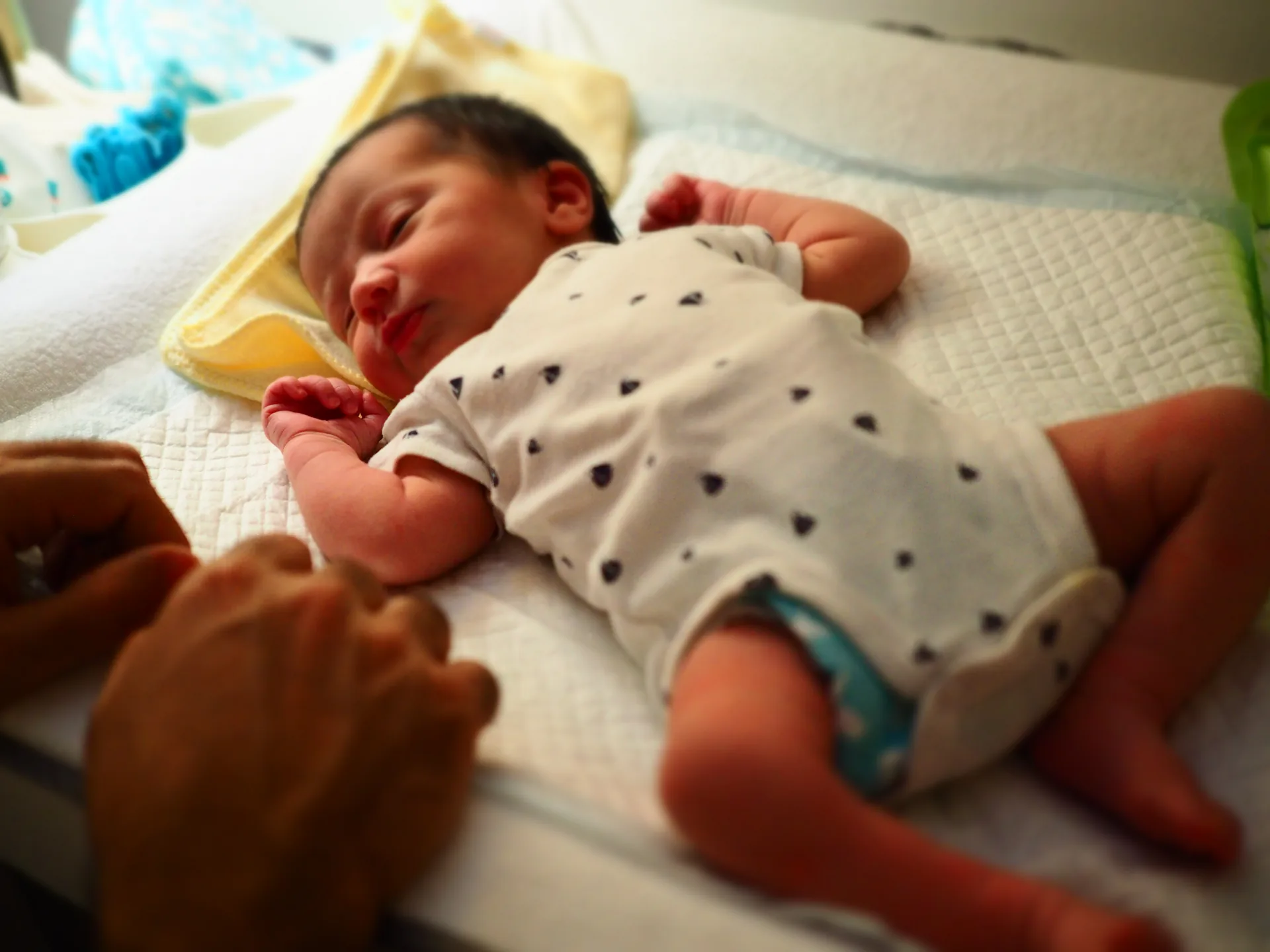 Charlotte tenderly holding a sleeping newborn during a postpartum home visit in Singapore