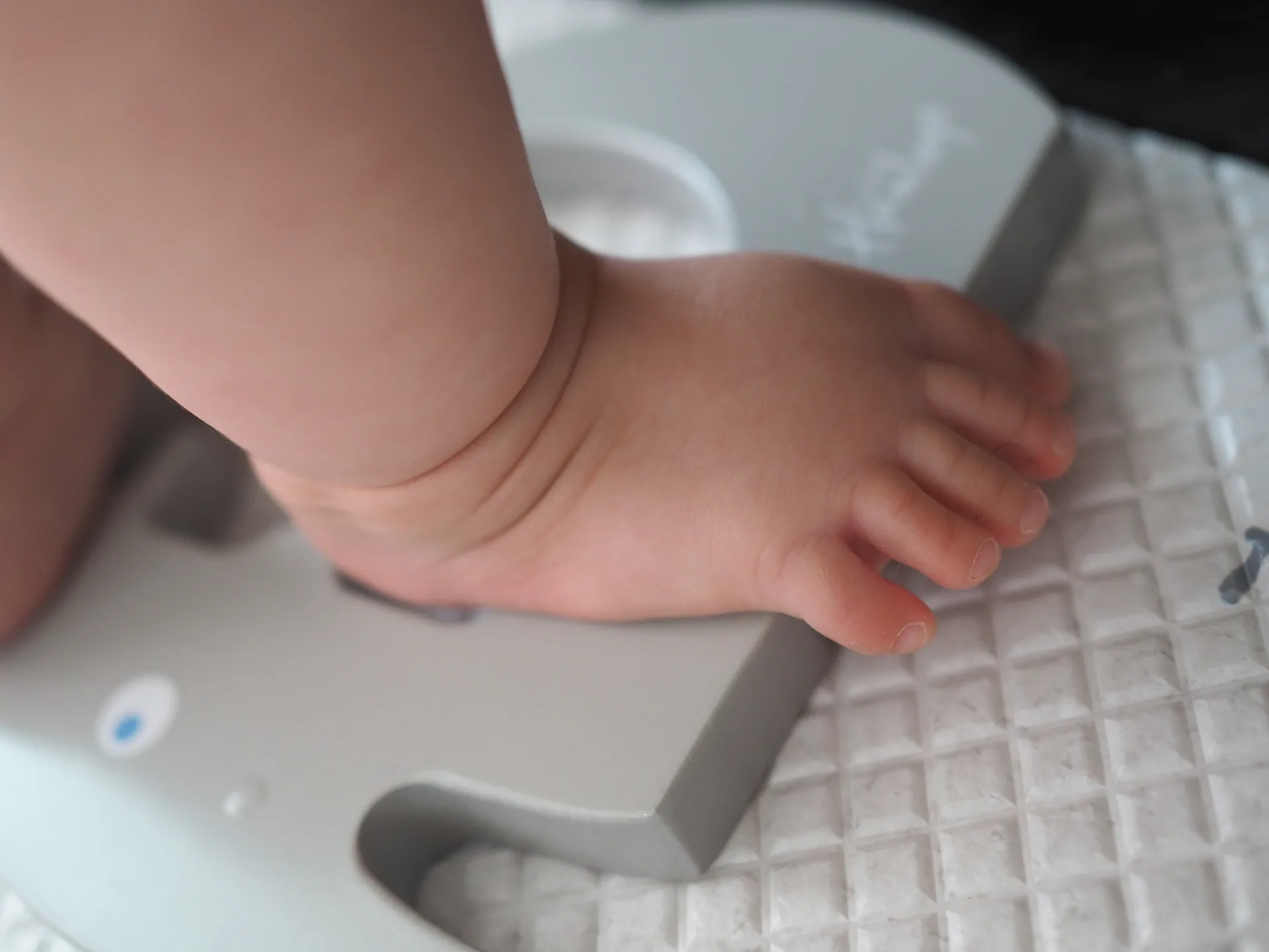 Charlotte weighing a newborn on a baby scale during a postpartum home visit in Singapore
