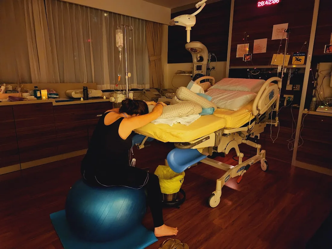 Charlotte as a birth doula on a birthing ball, supporting a labouring mother in Singapore