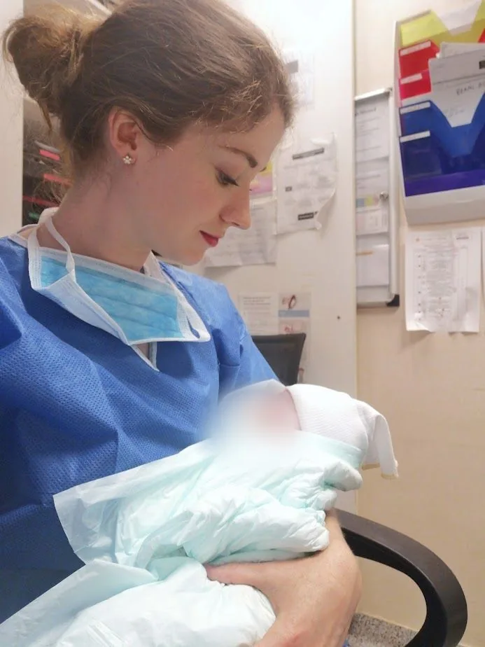 Charlotte as a midwife in France, holding a newborn baby