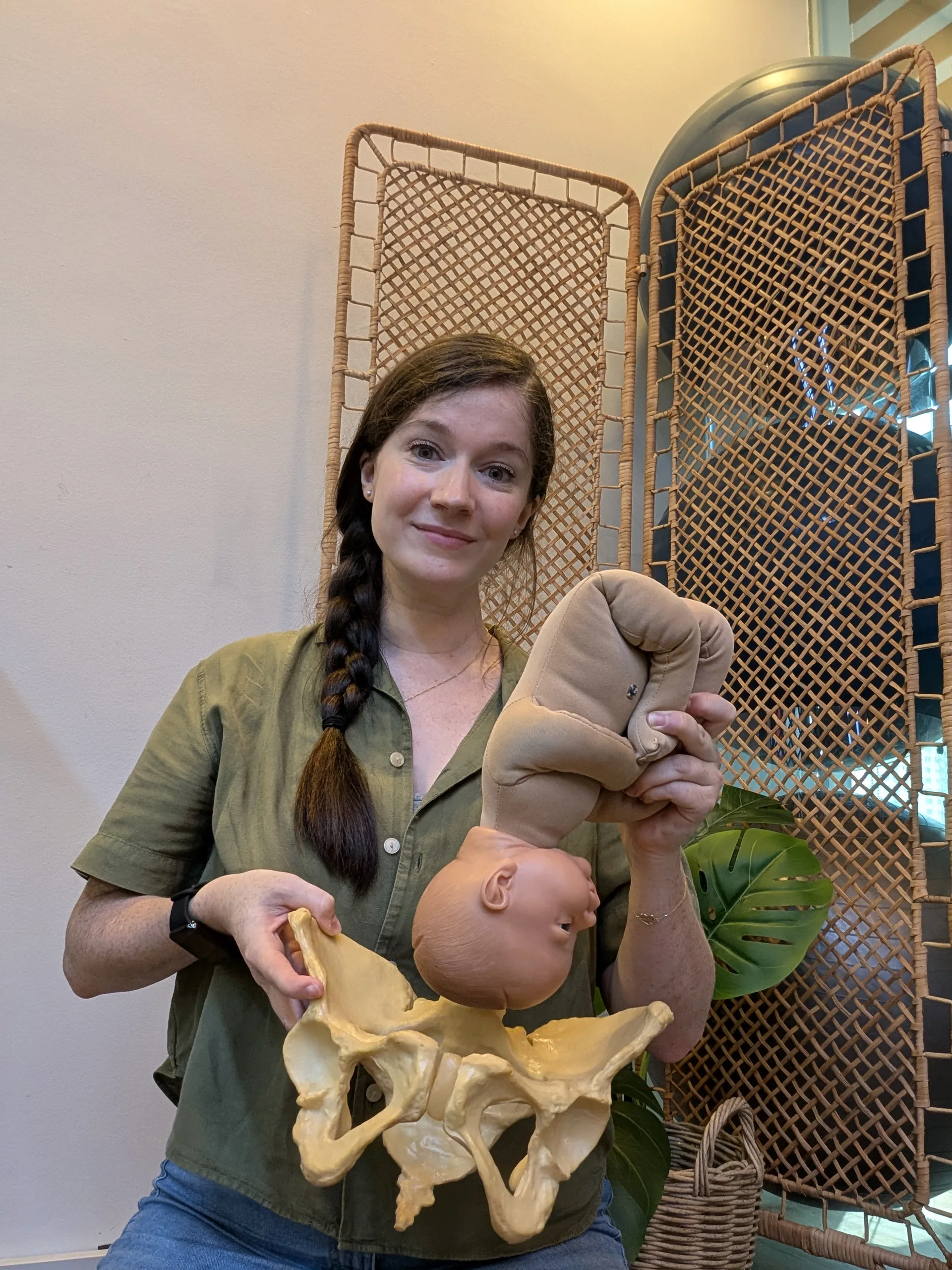 Charlotte teaching baby positioning with anatomical pelvis and baby model during a private antenatal class in Singapore